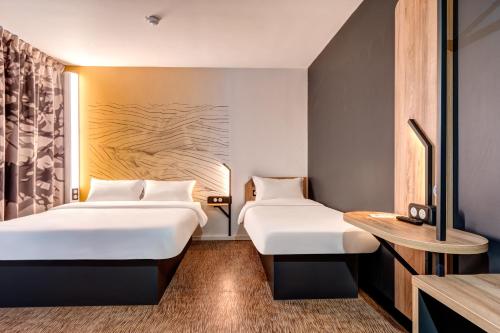布瓦达西B&B HOTEL Bois d'Arcy Saint Quentin en Yvelines的酒店客房设有两张床和一张桌子。