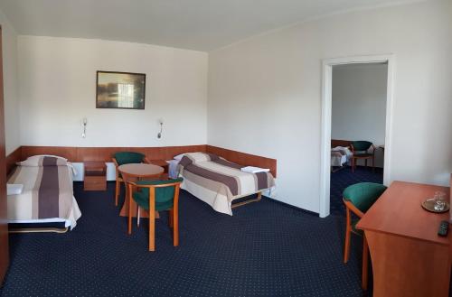 罗兹Hotel Alicja的一间设有两张床和一张桌子及椅子的房间