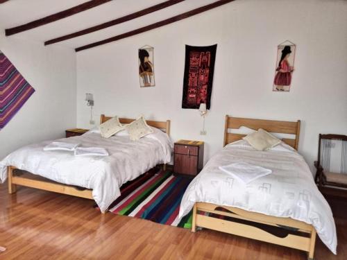 Comunidad YumaniHostal Inca Uma的配有白色墙壁和木地板的客房内的两张床