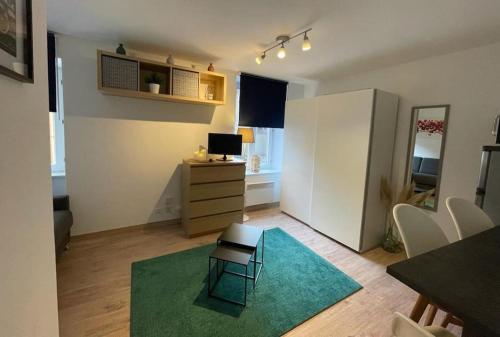 萨维尔纳Studio zone piétonne à Saverne的一间小客厅,配有绿色地毯和一张书桌