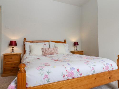 海斯Castle Cottage的一间卧室配有一张带花卉床罩和两盏灯的床。