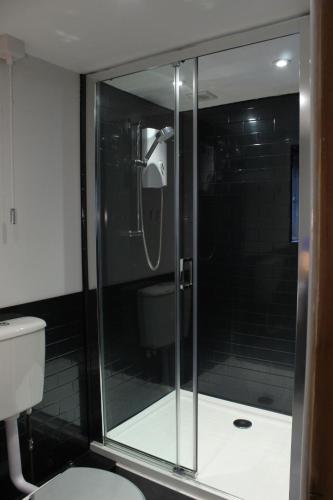 哈罗盖特Acomb Lodge的一间带卫生间的浴室内的玻璃淋浴间