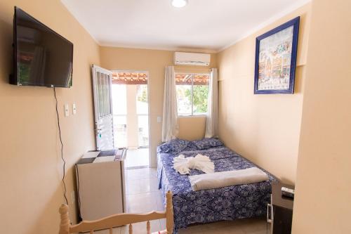瓜拉派瑞Pousada Três Praias的小房间设有床和电视