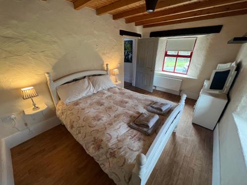 ManorhamiltonCarraun Cottage的一间卧室配有一张床,并在一间客房内配有电视。