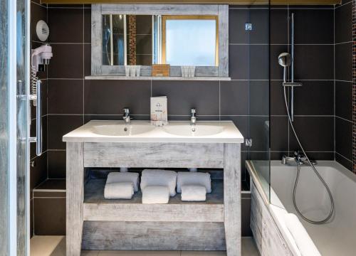 蒂涅Hôtel L'Aiguille Percée的浴室配有盥洗盆、镜子和浴缸