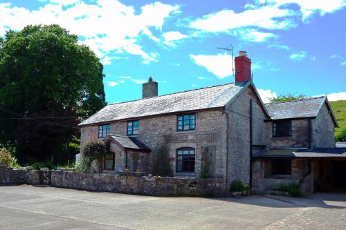 奥斯威斯Cynynion Uchaf - Countryside Farmhouse with Views的停车场里一座古老的石头房子