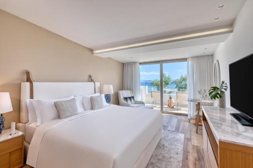 莫拉蒂卡Domes Miramare, a Luxury Collection Resort, Corfu - Adults Only的白色卧室设有一张大床和电视。