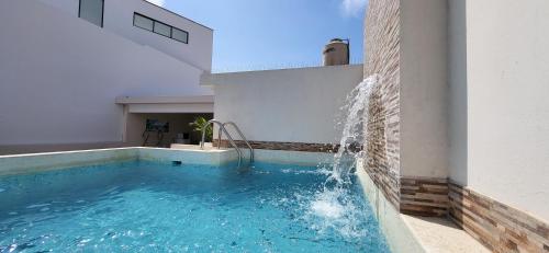 蓬塔赫尔莫萨L & P Apart Punta Hermosa的一座建筑物的一侧,设有一座带喷泉的游泳池