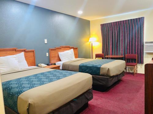 温斯洛Rodeway Inn Winslow I-40的酒店客房设有两张床和窗户。