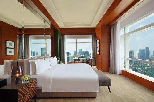 雅加达The Ritz-Carlton Jakarta, Pacific Place的卧室设有一张白色大床和大窗户