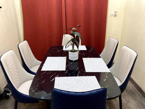 瓦加杜古Superbe mini-villa tout confort!的一张带白色椅子的黑桌和盆栽植物