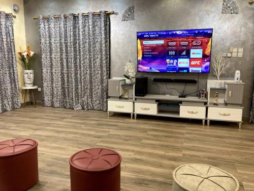瓦加杜古Superbe mini-villa tout confort!的客厅配有大屏幕电视和2张凳子