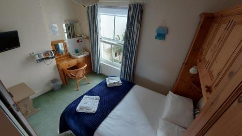 佩恩顿The Clifton at Paignton的一间卧室配有一张带蓝色床单的床和一扇窗户。