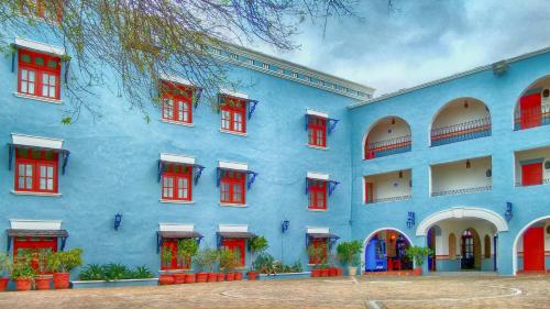 马塔莫罗斯HOTEL COLONIAL MATAMOROS的蓝色的建筑,有红色的窗户和树