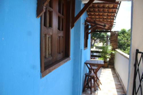 奥林达ROSÁRIO TEMPORADA Hostel的蓝色的建筑,窗户和门廊上的凳子