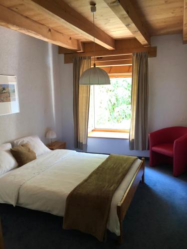 Le Noirmont伯格旅馆的一间卧室配有一张大床和一张红色椅子