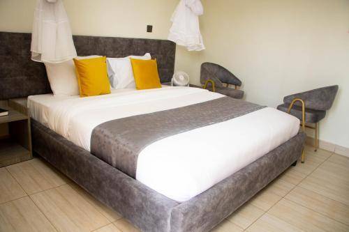SiayaDistinction Gardens的卧室配有一张带黄色枕头的大型白色床。