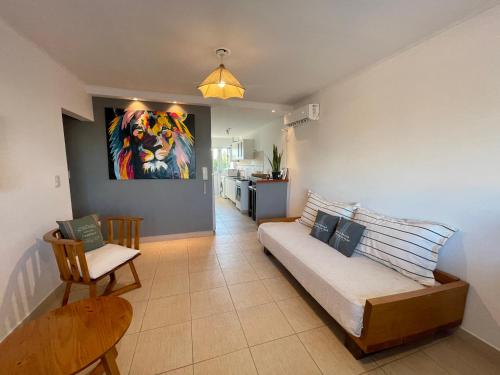特雷斯阿罗约斯Hermoso y cómodo dpto c/cochera Tres Arroyos的客厅配有沙发和墙上的绘画