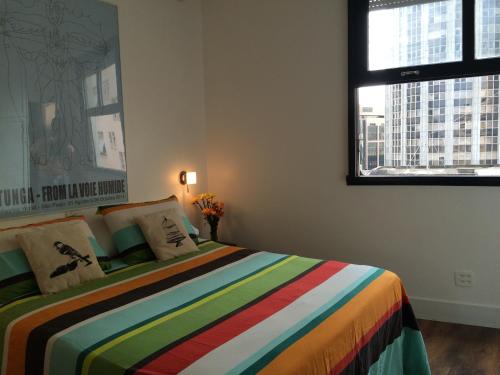 里约热内卢Studio Rio Beira Mar的一间卧室配有一张色彩缤纷的床和两个窗户