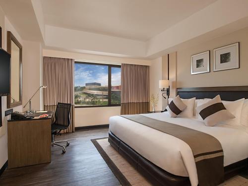 达沃市Seda Abreeza Hotel的配有一张床、一张书桌和一扇窗户的酒店客房