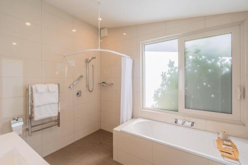 OtakiAnam Cara Gardens luxury Villa的白色的浴室设有浴缸和窗户。