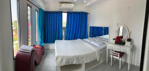 Tây NinhHotel MAI TUAN Chánh Môn A的一间卧室配有一张带蓝色窗帘和镜子的床