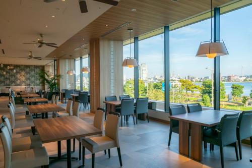 松江市一畑酒店的餐厅设有桌椅和大窗户。