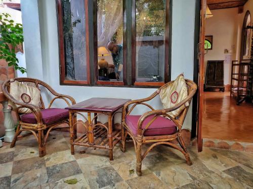 廊开玛米花园旅馆的一张桌子、两把椅子和一张带紫色座椅的桌子
