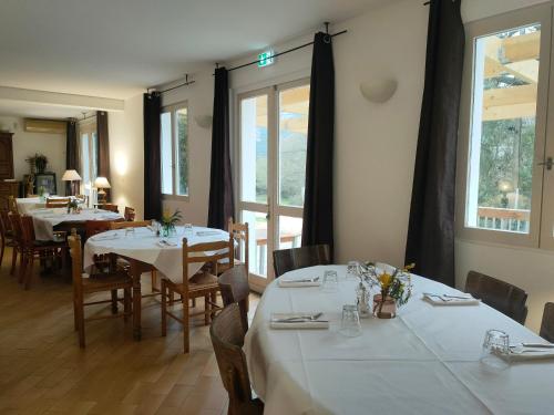 Occhiatanaauberge de tesa的餐厅设有白色的桌椅和窗户。
