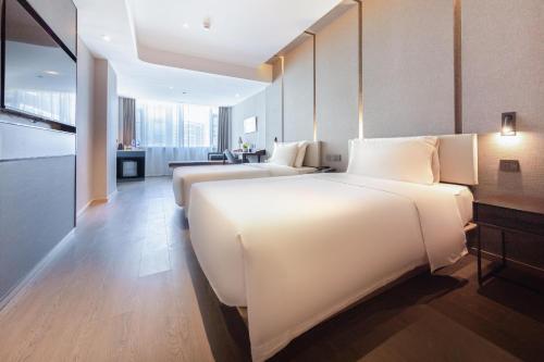 宝安深圳宝安国际会展中心亚朵酒店的一间白色的大卧室,内配两张床