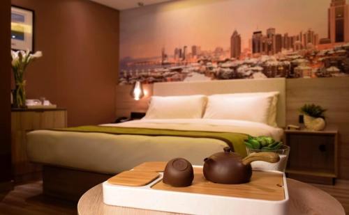 青岛青岛奥帆中心五四广场亚朵酒店的卧室配有一张大床,墙上挂有绘画作品