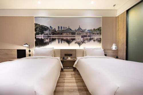 武汉武汉天河机场腾龙大道地铁站亚朵酒店的两张位于酒店客房的床,墙上挂着一幅画