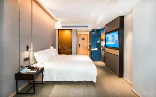 宝安深圳宝安国际机场亚朵酒店的酒店客房设有一张大床和一台电视。
