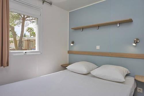 勒格罗-迪鲁瓦La petite Camargue的一间卧室配有带两个枕头的床和窗户