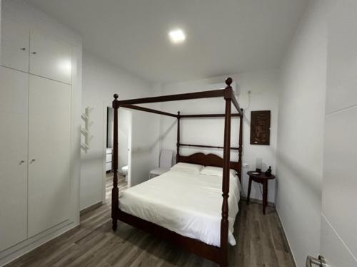 大桑卢卡尔Joju的卧室配有带白色床单的天蓬床