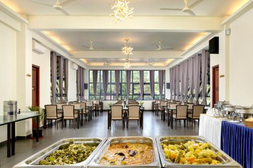 玛纳多迪Fern Tree Resort的大房间设有桌椅,展示着食物
