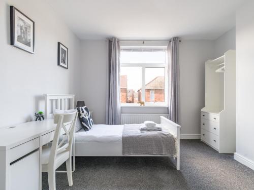 BedlingtonLilys Apartment 2- 2bedroom, Northumberland的一间卧室配有一张床、一张书桌和一个窗户。