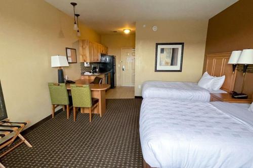 威利斯顿MainStay Suites Williston的酒店客房设有两张床、一张桌子和一间厨房。