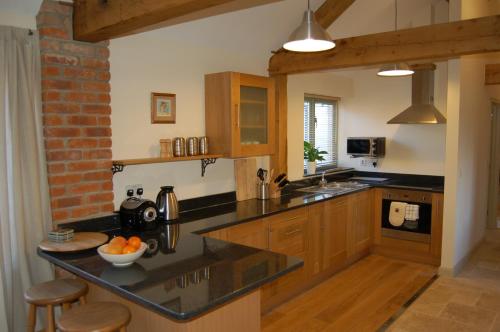 格拉斯顿伯里金银花农场度假屋的厨房配有黑色台面和木制橱柜