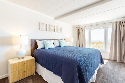 大洋城Sandpiper Dunes 105的白色卧室设有蓝色的床和窗户