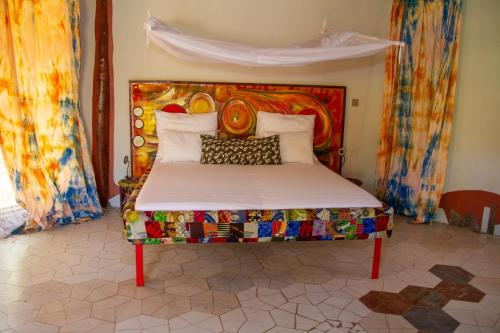 TanjiMama Africa Art Residence & Art Center Gambia的一张带色彩缤纷床头板的床