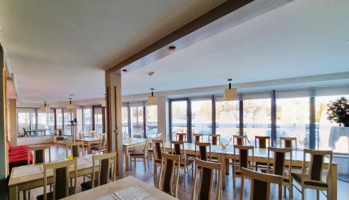罗亚马雷什酒店的餐厅设有木桌和椅子以及大窗户。