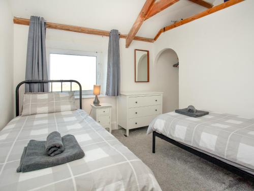 廷塔杰尔Mews Cottage的一间卧室设有两张床和窗户。