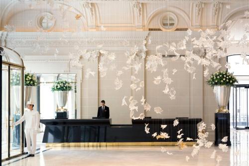 巴黎巴黎半岛酒店的站在带柜台的大厅里身着白色西装的人