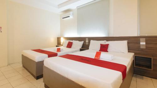 马尼拉RedDoorz at V Plaza Hotel Manila的酒店客房 - 带两张带红色枕头的床