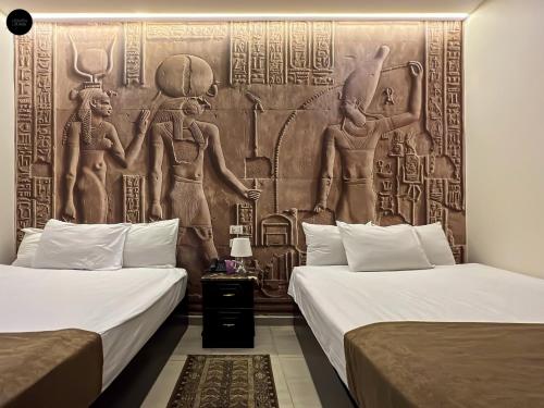 开罗Giza Pyramids View Inn的客房设有两张床和壁画墙