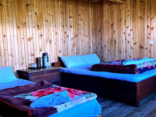 佩林Phamlhakhang Ecohomestay的木墙客房的两张床