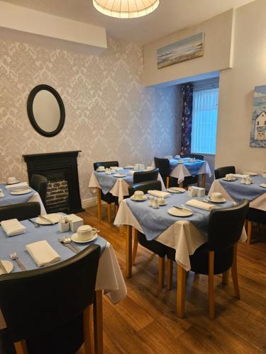 斯卡伯勒Hermosa Guest House的一间配备有蓝色桌椅和壁炉的用餐室