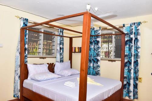 迪亚尼海滩Double room in a villa的一间卧室设有四柱床和两个窗户。