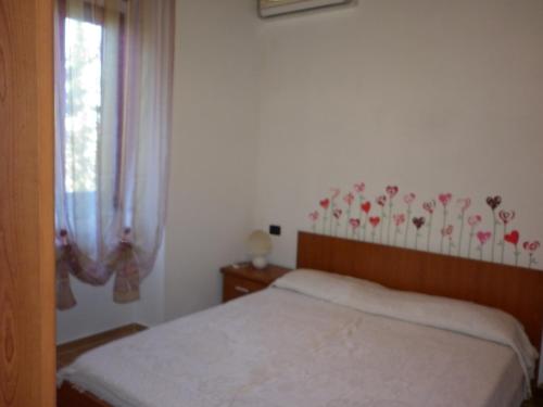 里奥马里纳Appartamenti Piombino Isola d'Elba的一间卧室设有一张床,墙上设有鲜花窗户。
